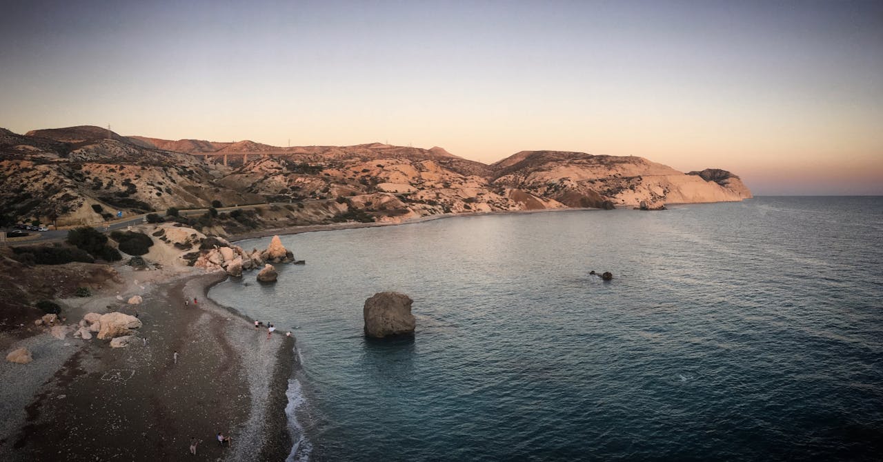 A stunning aerial view of Petra tou Romiou, Cyprus, capturing the serene coastline at sunset.
