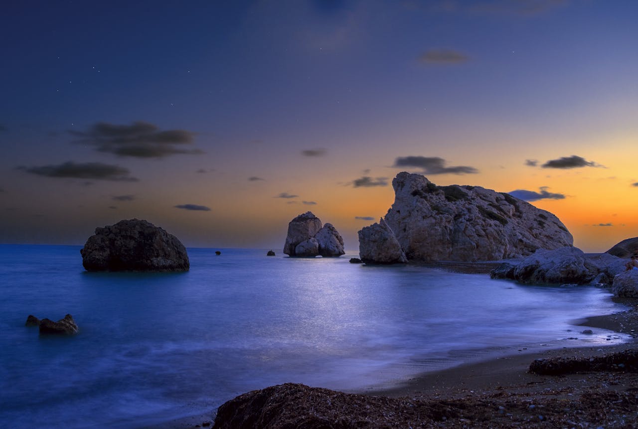 A serene view of rocky Kouklia beach in Cyprus at twilight, capturing the gentle waves and dusk sky.